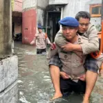 Brimob Polda Metro Gendong Warga Sakit Terjebak Banjir di Cengkareng, Jakarta Barat